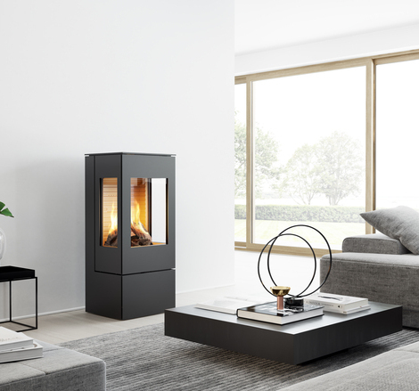 Gas-Kaminofen NEXO 100 in Schwarz mit Stahltür und zwei Seitenfenstern in einem modernen, hellen Wohnraum