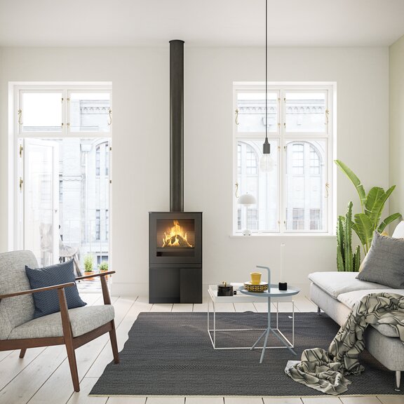 Poêle à gaz Q-TEE 2 avec porte en acier et socle pratique dans un appartement stylé au cœur de la ville