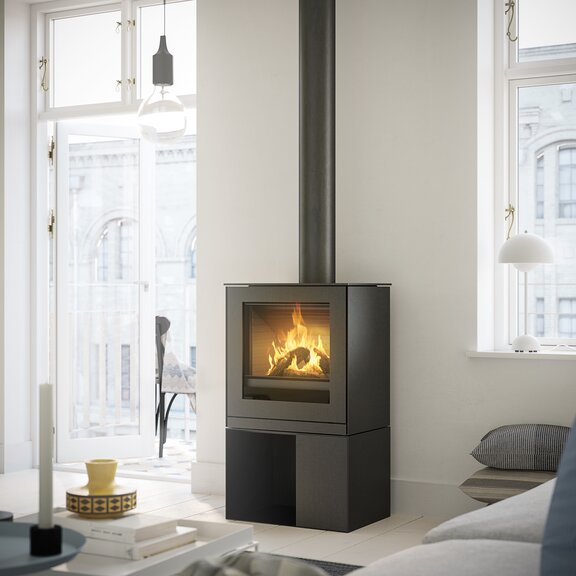 Poêle à gaz Q-TEE 2 avec porte en acier et socle pratique dans un appartement urbain