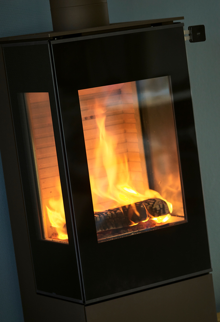 Poêle à bois NEXO 120 noir avec porte de foyer plein verre et deux vitres latérales offrant une vue directe sur le feu en combustion