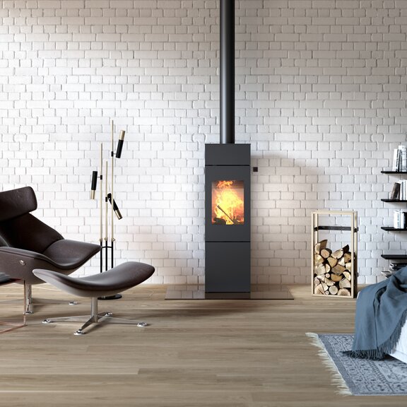 Poêle à bois NEXO 140 en noir avec porte en acier dans un loft de style industriel avec une grande bibliothèque