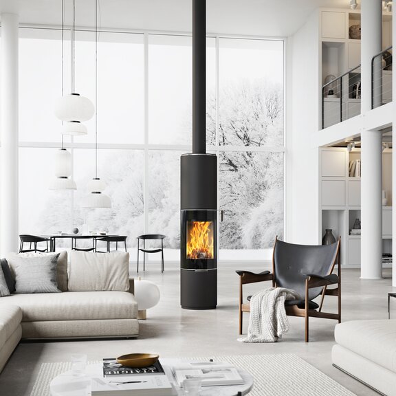 Poêle à bois PILAR en noir avec porte de foyer plein verre comme poêle rond pivotant au milieu d'une immense pièce à vivre de style scandinave