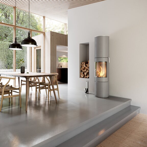Poêle à bois PILAR en nickel avec porte en acier et poignée de porte en acier inox dans une salle à manger au style d'aménagement moderne