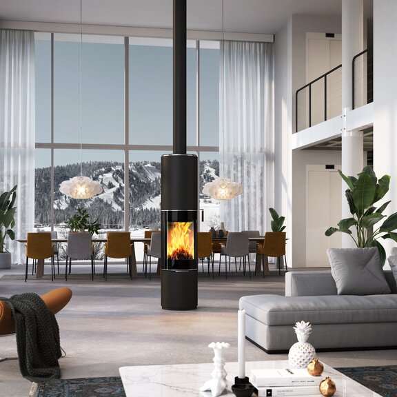 Poêle à bois PILAR en noir avec porte de foyer plein verre comme poêle rond pivotant au milieu d'une immense pièce à vivre