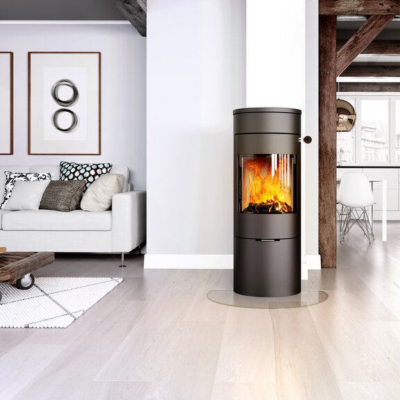 Poêle à bois VIVA 120 L en noir avec porte en acier dans un espace de vie lumineux et ouvert