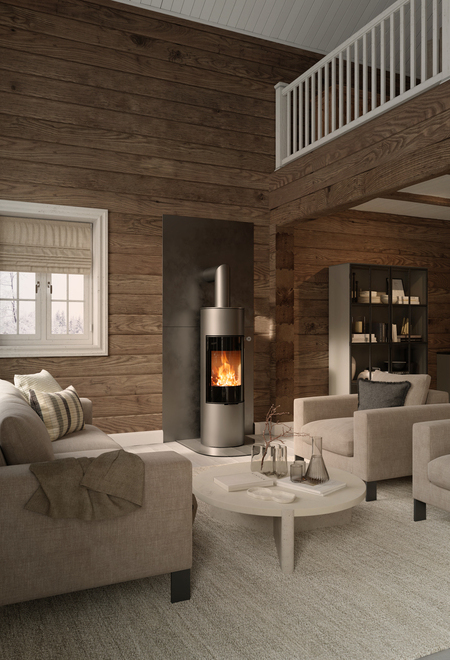 Poêle à bois VIVA 140 L en couleur platine avec porte de foyer plein verre sur mur en bois dans une maison d'habitation rustique